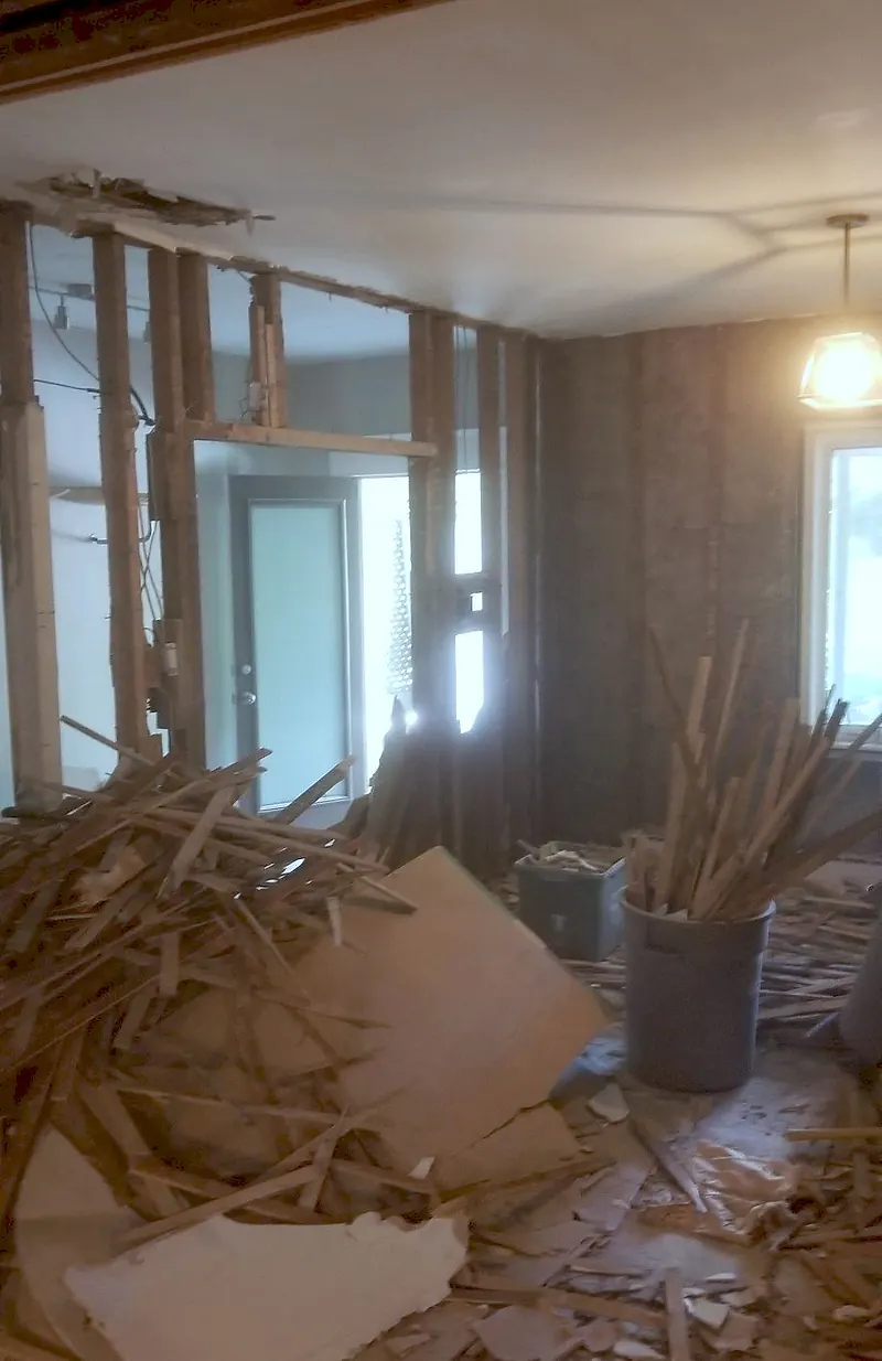 Room stripped to the framing with broken plaster and lath piled on the floor