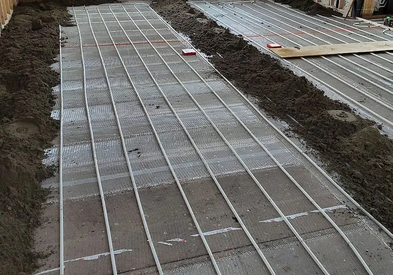 Heating tubes on mesh in runs, with mounds of dry pack mortar placed between them