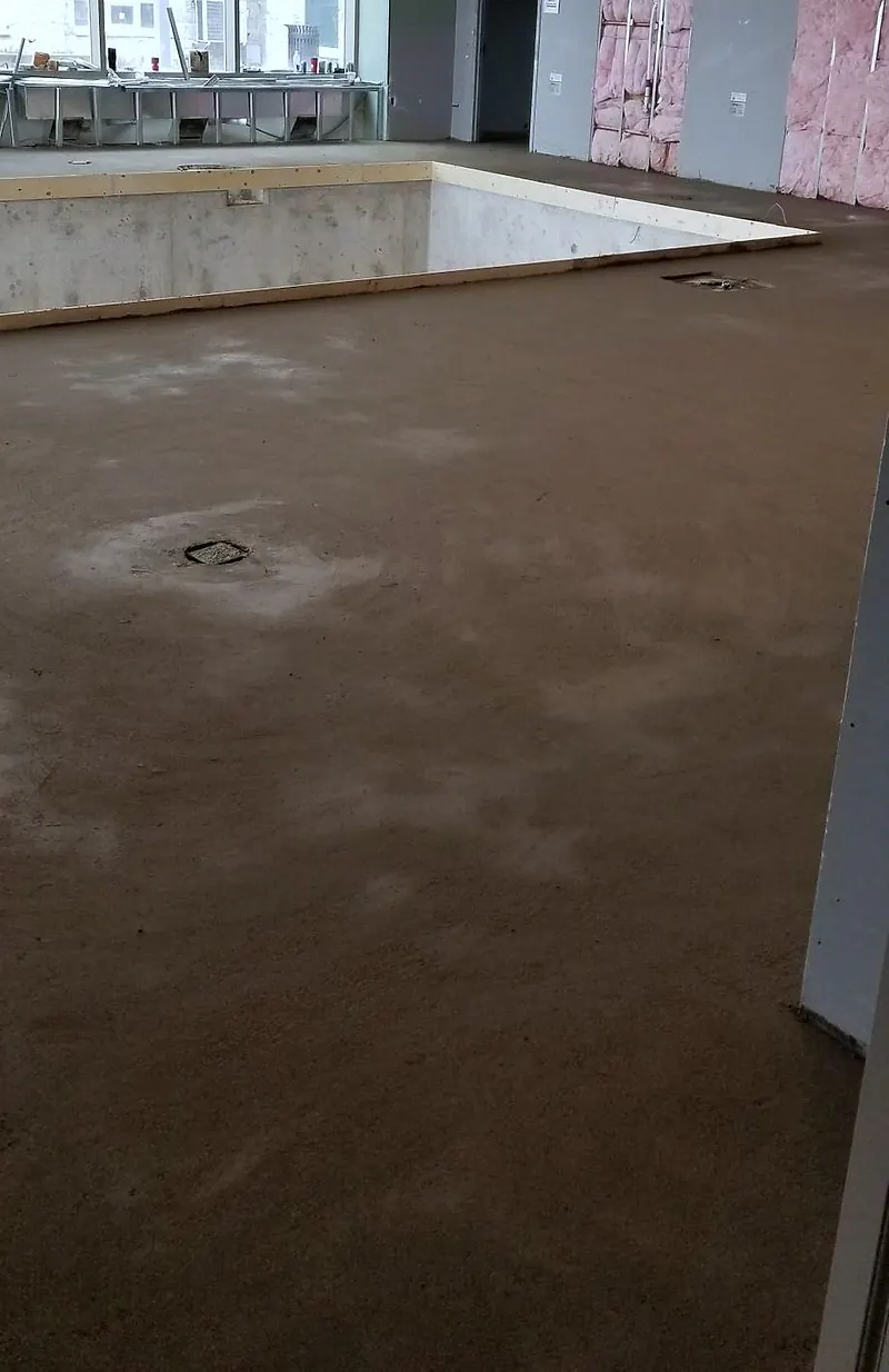Finished mortar deck around a rectangular indoor pool shell, with large windows behind