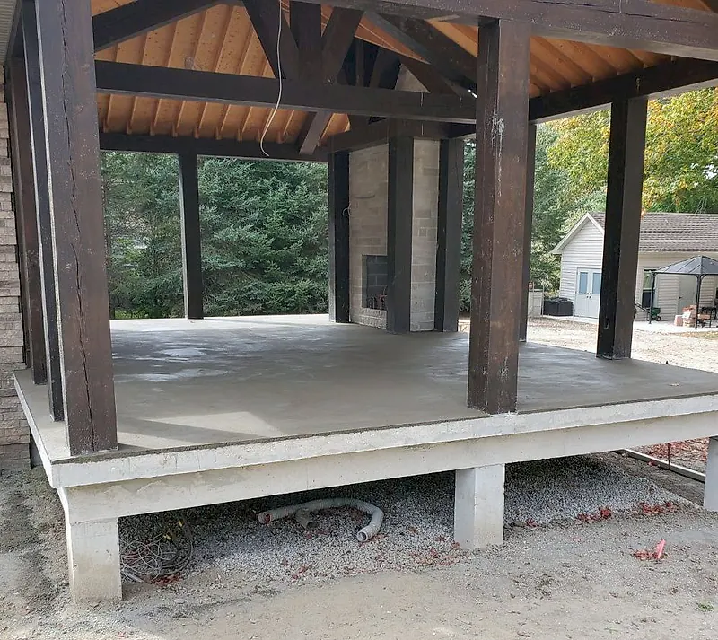 Fresh mortar bed screeded on a raised platform under a dark timber pavilion
