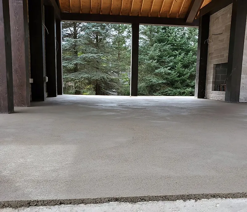 Low view across a fresh screeded bed inside a timber pavilion, evergreen trees beyond