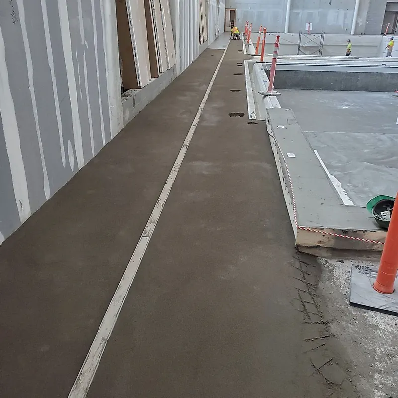 Long finished mortar strip along a wall beside an indoor pool, divided by a rail line