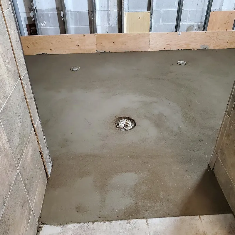 Mortar shower floor with a centre drain opening and two small outlets at the back, between tiled side walls